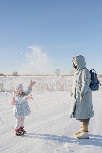 Een jonge zwangere vrouw speelt in de winter buiten met haar baby