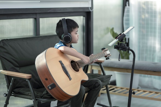 Een jongen die gitaar leert spelen Concentratie op het spelen van de muziek