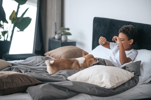 Een jongen die in bed ligt en een hond samen met hem