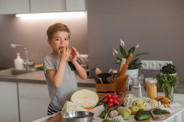 Een jongen die met groenten in de keuken kookt