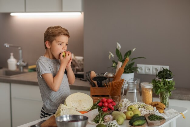 Een jongen die met groenten in de keuken kookt