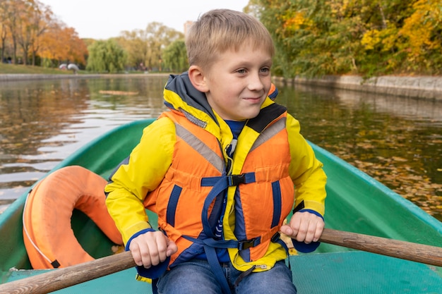 Een jongen die op een houten boot roeit