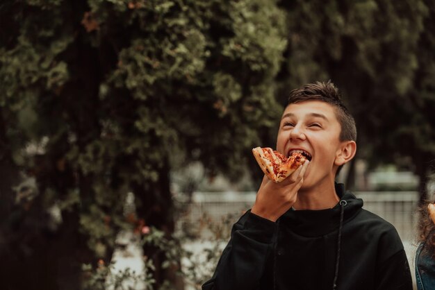 Een jongen eet pizza tijdens een lunchpauze op school Selectieve focus Foto van hoge kwaliteit