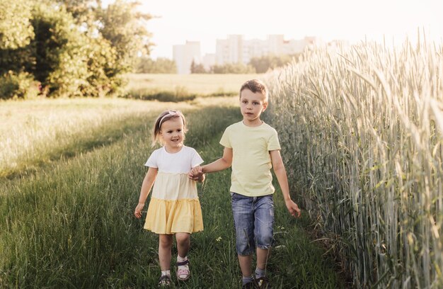 Een jongen en een meisje, broer en zus spelen in de zomer in het veld. fijne zomervakantie. jongen en meisje op landweg. tarwe veld