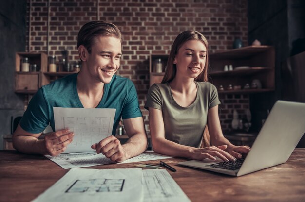 Foto een jongen en een meisje kijken naar een notebook zittend aan een werktafel. twee medewerkers zitten op kantoor en werken.