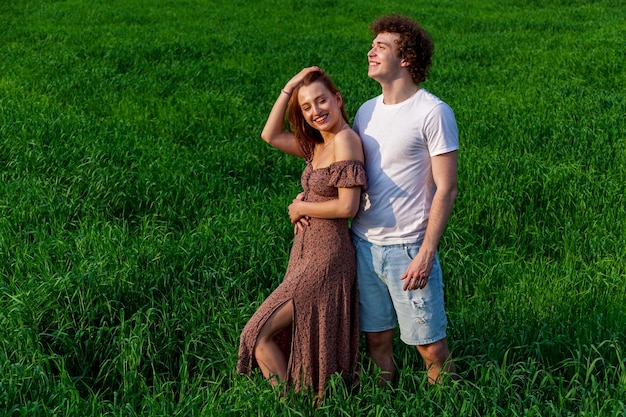 Een jongen en een meisje knuffelen op een groen veld.