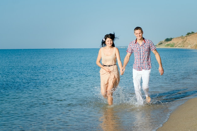 Een jongen en een meisje lopen langs de kust, zwemmen in het water