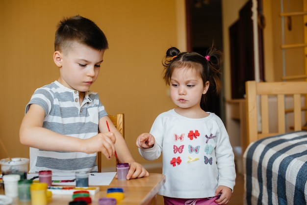 Een jongen en een meisje spelen samen en schilderen. Recreatie en amusement. Blijf thuis.