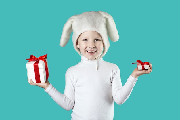 Een jongen gekleed als een witte haas probeert een geschenk op mint achtergrond te kiezen