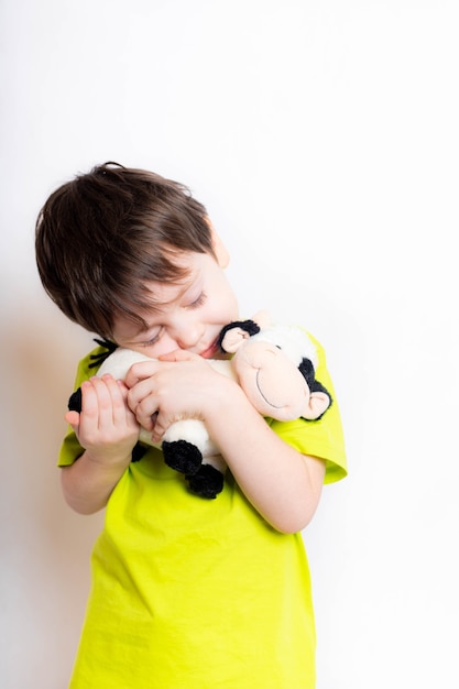 Een jongen houdt een stierenspeelgoed vast. Leuk kind met een stuk speelgoed. Speelgoedstier, symbool van het jaar. 2021. Nieuwjaar. Leuke emoties