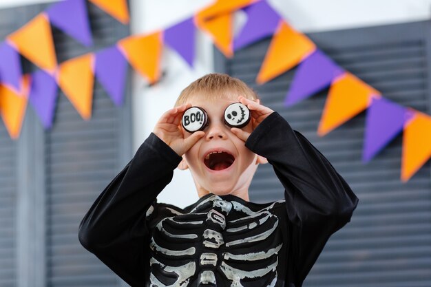 Een jongen in een skeletkostuum is aan het dollen en spelen met koekjes