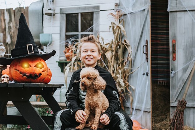 Een jongen in een skeletkostuum met een hond op de veranda van een huis dat is ingericht om een Halloween-feest te vieren