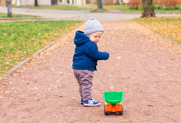 Een jongen in een warme jas en muts loopt in het park