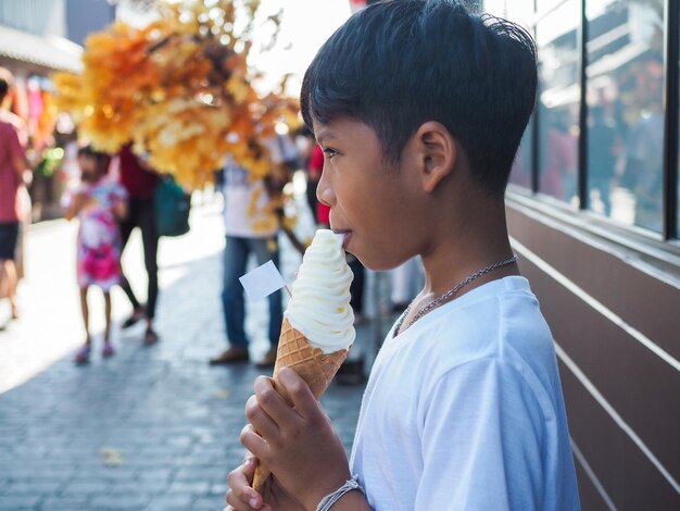 Een jongen in een wit overhemd eet een ijsje