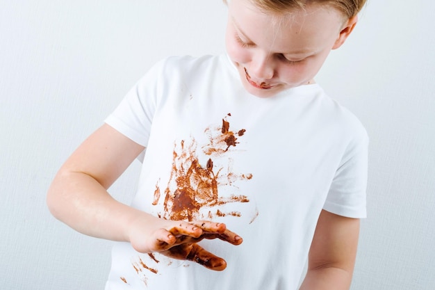 Een jongen in een wit overhemd met chocolade erop