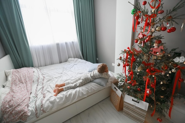 Foto een jongen in pyjama ligt op een bed bedekt met een wit laken.