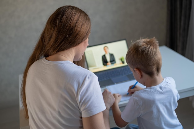 Een jongen leert het alfabet met een laptopleraar Afstandsonderwijs via videoconferentie Voorschools onderwijs op afstand