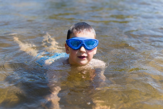 Een jongen met een blauwe bril zwemt in het meer