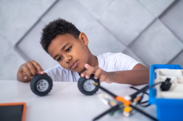 Een jongen met een donkere huidskleur die met speelgoedautowielen speelt