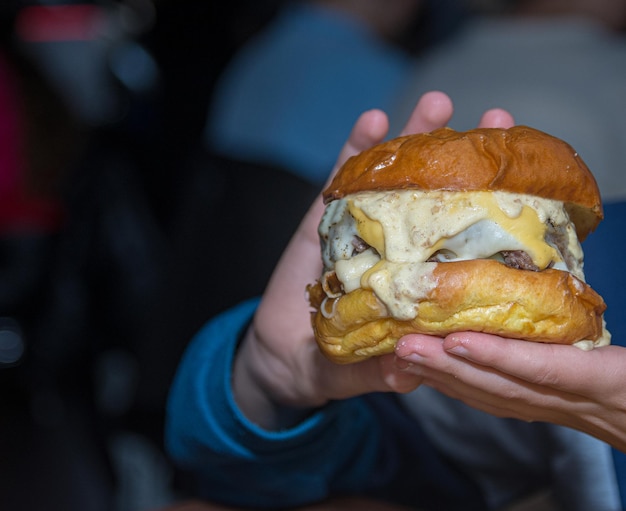 Een jongen met een hamburger vol kaas.