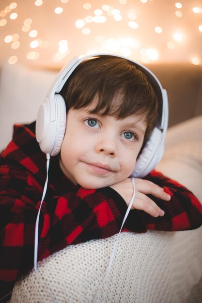 Een jongen met een koptelefoon ligt op de banklevensstijl. De jongen luistert naar muziek.