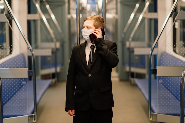 Een jongen met een medisch masker staat verdrietig bij het treinraam, een kind reist alleen.