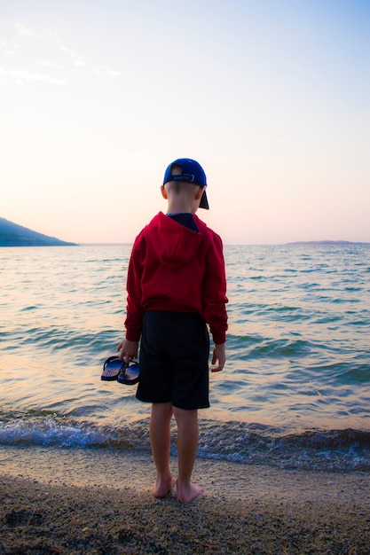 Een jongen met een pet voor wandelingen langs de kustlijn van het meer psychologische rust van kinderen uit iso...