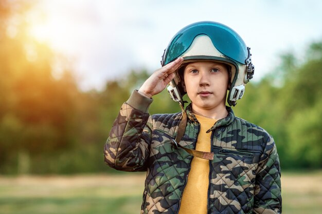 Een jongen met een pilotenhelm salueert.