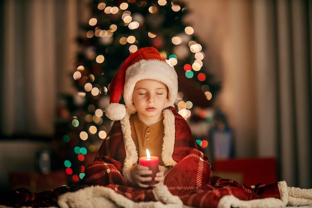 Een jongen met gesloten ogen zit thuis op Kerstmis en oudejaarsavond en doet een wens.