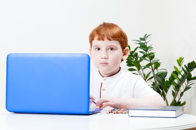 Een jongen met rood haar leert op afstand via een computer en internet