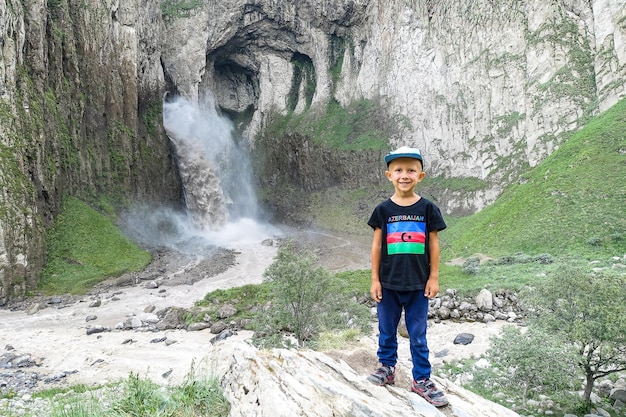 Een jongen op de achtergrond van de TuzlukShapa-waterval op het grondgebied van KabardinoBalkarië Kaukasisch Rusland