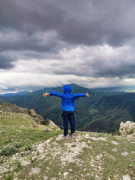 Een jongen op de achtergrond van een adembenemend uitzicht op de bergen tijdens een onweersbui in Dagestan