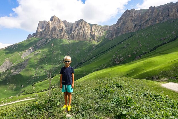 Een jongen op de achtergrond van het groene landschap van de Aktoprak-pas in de Kaukasus, Rusland juni 2021