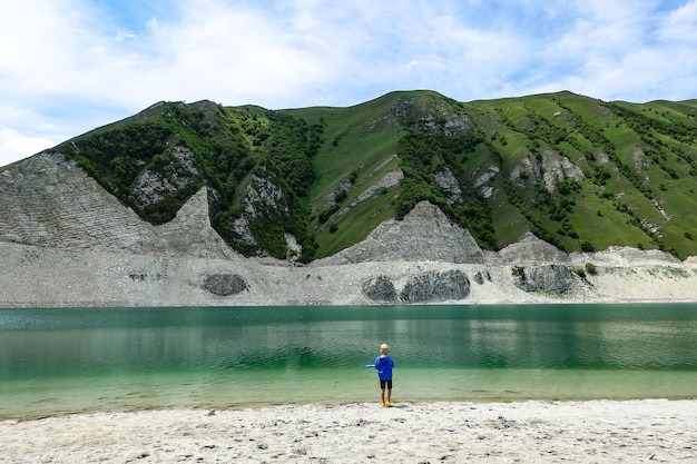 Een jongen op de achtergrond van het Kezenoyam-meer in de bergen van de Kaukasus in Tsjetsjenië, Rusland juni 2021