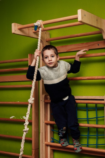 Een jongen op een Zweedse muur Indoor sport Jongen doet sport op horizontale balken