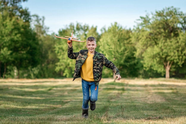 Een jongen rent over het veld en lanceert een speelgoedvliegtuig.