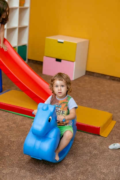 een jongen rijdt op een plastic paard in de speelkamer