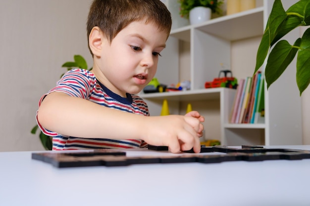 Een jongen speelt een bordspel met dominostenen