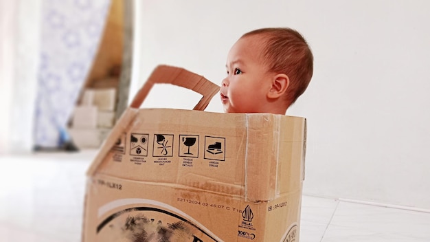 Een jongen speelt in een speelgoedwagen gemaakt van karton dat wordt gebruikt voor het verzenden van pakketten