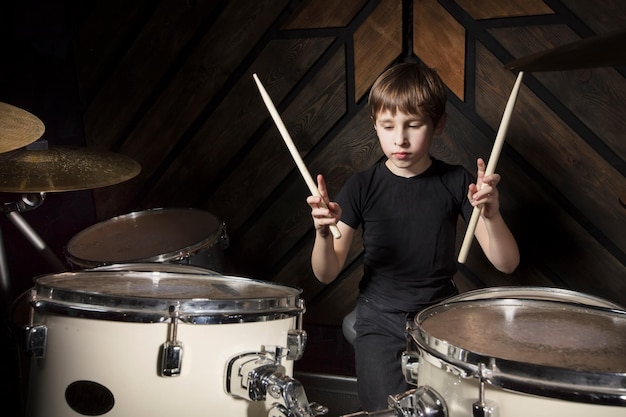 Een jongen speelt met een drumstick Het kind achter het drumstel