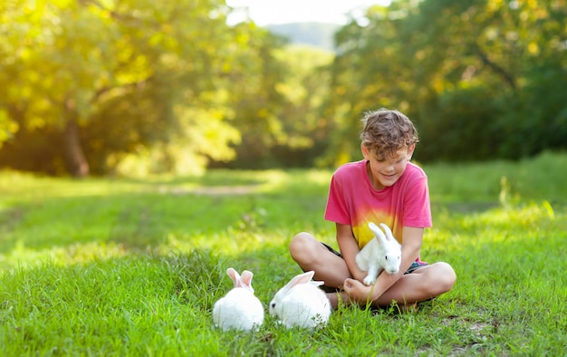 Een jongen speelt met witte konijnen op een groene open plek