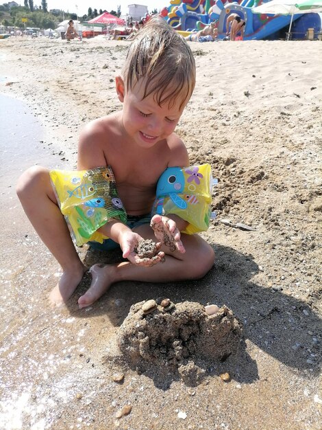 Een jongen speelt met zand en een zandkasteel.