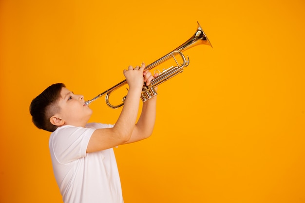 Een jongen speelt trompet. De mooie tienerjongen speelt trompet muzikaal instrument