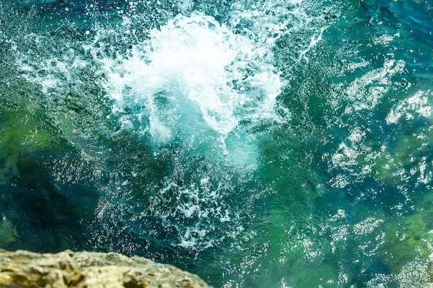 Een jongen springt van de klif in de zee met grote waterplons op een hete zomerdag Vakantie op het strand Het concept van actief toerisme en recreatie