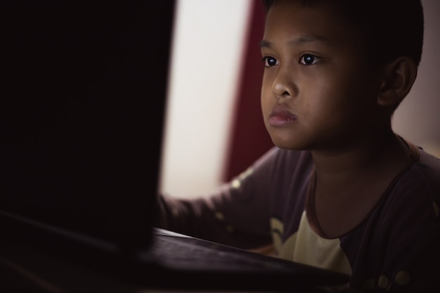 Een jongen studeert thuis online op zijn laptopcomputer.