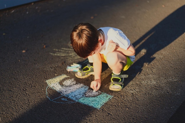 Een jongen tekent een levensstijl met kleurpotloden op het asfalt Kinderlessen Kindertekeningen Kinderpsychologie