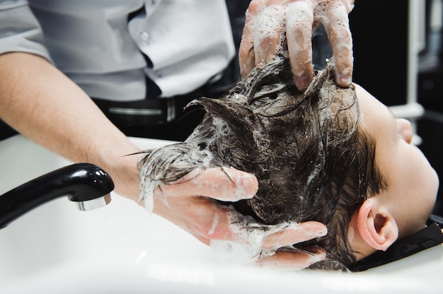 Een jongen wordt gewassen door de kapper in herenkapper