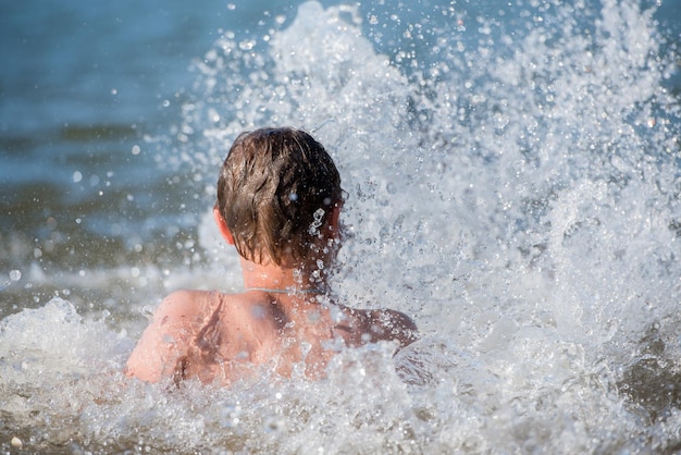 Een jongenstiener zwemt in een straal water, een concept van een strandvakantie