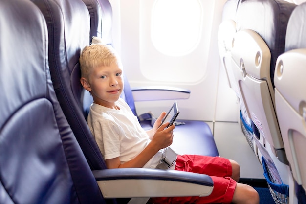 Een jongetje in een vliegtuig dat een e-boek leest of op een tablet speelt tijdens een lange vlucht