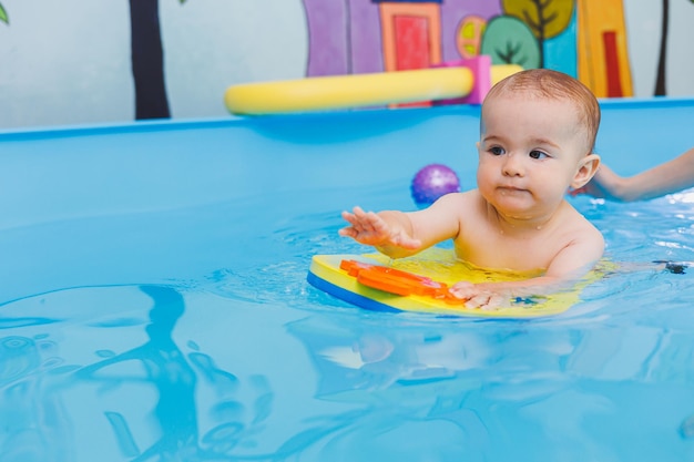 Een jongetje leert zwemmen in een babybadje Ontwikkeling van kinderen Eerste zwemlessen voor kinderen